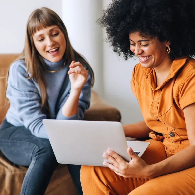 female employees looking at laptop smiling