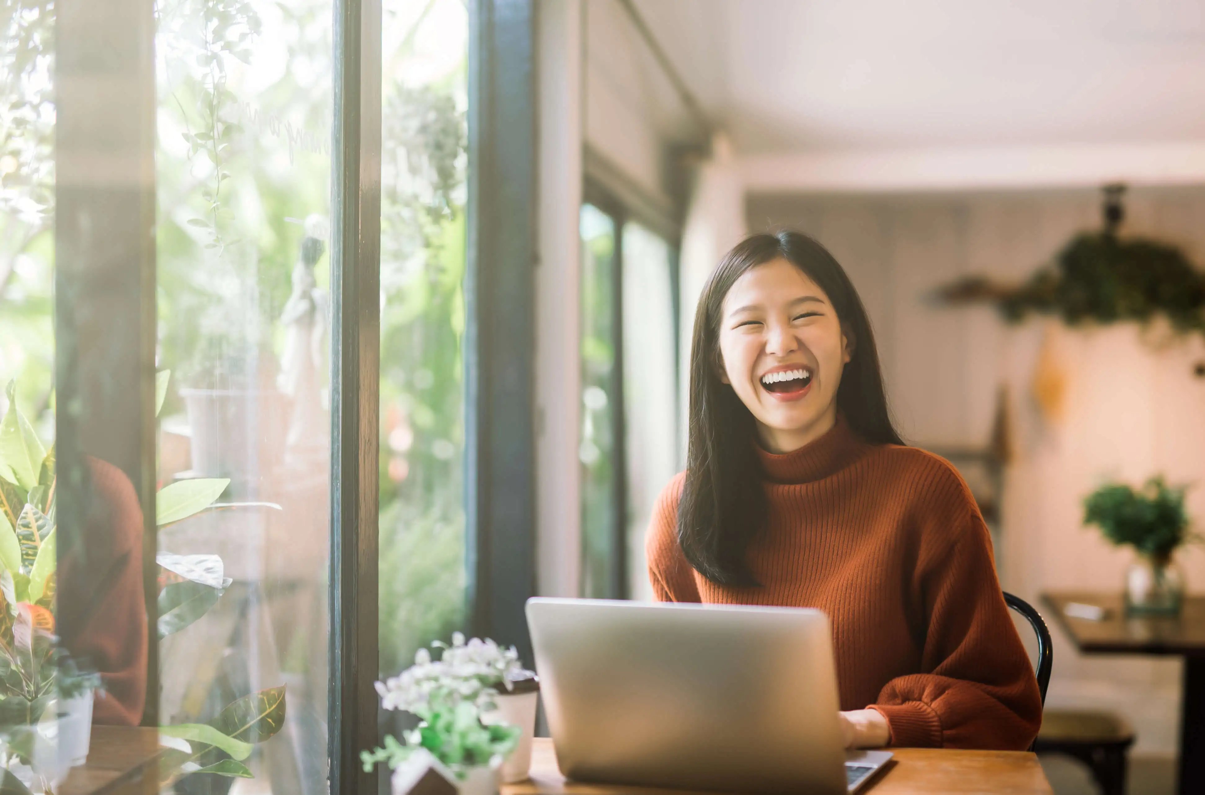 Woman laughing behind laptop