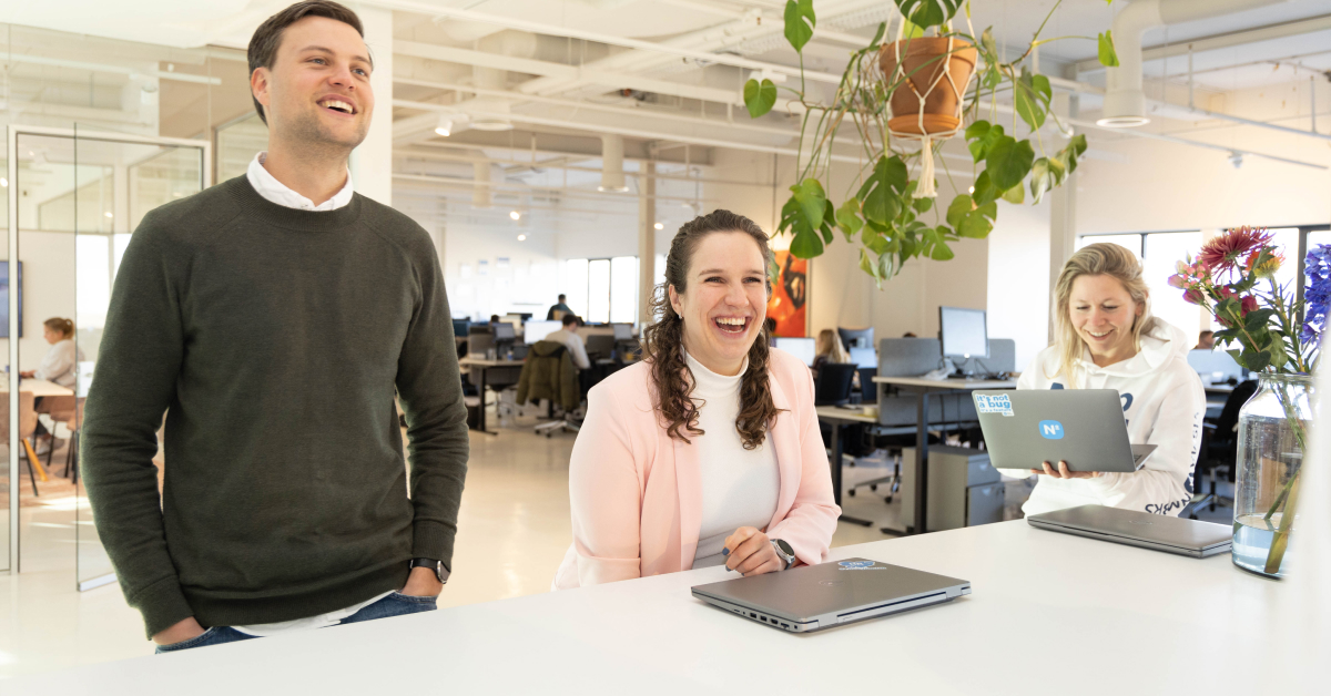 Collega's die staan aan een tafel en met elkaar lachen